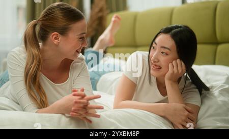 Zwei glückliche multiethnische Frauen Freunde weibliche Vielfalt Mädchen Kaukasische Frau im Gespräch mit asiatischen Mädchen teilen Nachrichten lachend lächelnd zeigen Stockfoto