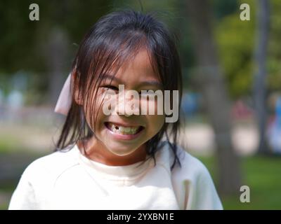 Porträt eines lächelnden kleinen Mädchens in einem Park an einem sonnigen Tag. Stockfoto