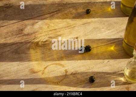 Schwarze Oliven auf Schatten und Reflexionen von Ölflaschen Stockfoto