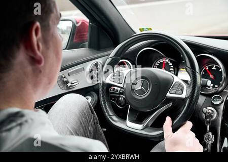 Bayern, Deutschland - 14. Dezember 2024: Ein junger Mann fährt in einem Auto mit Blick auf die Straße, während er das Lenkrad hält. Der Innenraum des Autos zeigt ein modernes Cockpit mit Tachometern und Bedienelementen *** ein junger Mann fährt in einem Auto mit Blick auf die Straße, während er das Lenkrad hält. Der Innenraum des Autos zeigt ein modernes Cockpit mit Tachometern und Bedienelementen Stockfoto