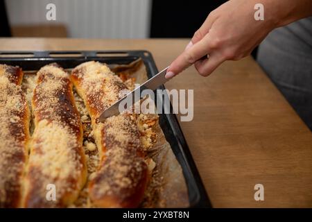 Frisch gebackenes Brot, das gerne auf einer rustikalen Holzoberfläche mit köstlichem Aroma geschnitten wird Stockfoto