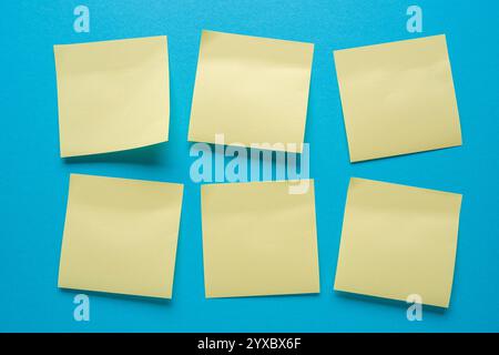 Leere Post-it-Notizen hängen in der richtigen Reihenfolge auf blauem Hintergrund Stockfoto