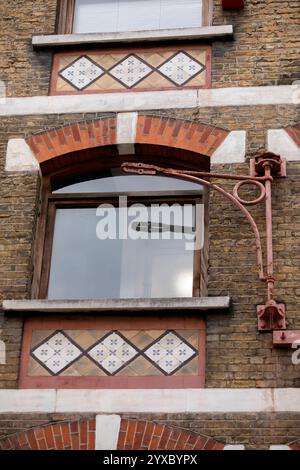 LONDON, Großbritannien - 22. OKTOBER 2021: Alte schmiedeeiserne Hebebühne und Fenster mit viktorianischen Fliesen auf dem Dairy Supply Company Gebäude an der Ecke der Coptic Street Stockfoto