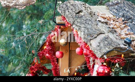 Rustikale Weihnachtsdekoration mit roter Girlande und Holzdach in der Natur Stockfoto