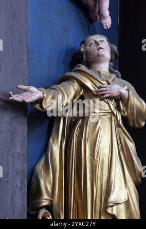 Johannes unter dem Kreuz, Statue auf dem Altar der Heilig-Kreuz-Versteigerung in der Franziskanerkirche der Heiligen Dreifaltigkeit in Slavonski Brod, CR Stockfoto