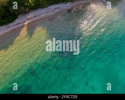 Bei dieser Aussicht aus der Vogelperspektive trifft das ruhige türkisfarbene Wasser auf ein Kieselstrand. Stockfoto