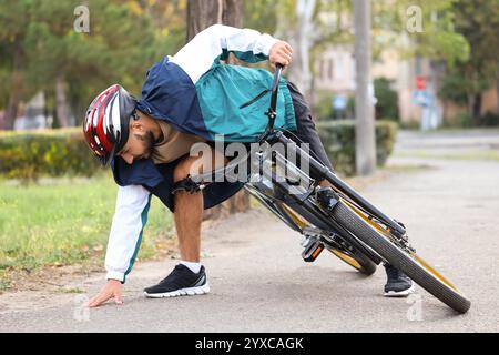 Junger Mann, der aufsteht, nachdem er draußen vom Fahrrad gefallen ist Stockfoto