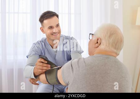 Die Krankenschwester misst den Blutdruck eines kranken älteren, Reifen männlichen Patienten, der ihn zu Hause besucht. Stockfoto