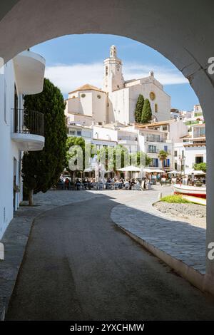 Der Stadtstrand von Port Alguer mit Bars, Restaurants und Cafés vor dem Hintergrund der Altstadt mit der gotischen Kirche Santa Maria in Cadaqués Stockfoto