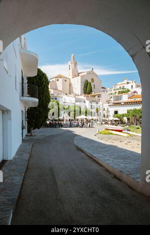 Der Stadtstrand von Port Alguer mit Bars, Restaurants und Cafés vor dem Hintergrund der Altstadt mit der gotischen Kirche Santa Maria in Cadaqués Stockfoto