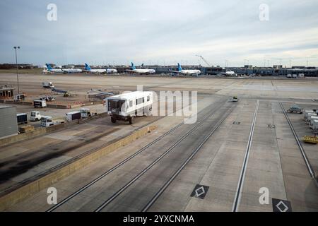 Eine geschäftige Szene am Flughafen Dulles, Washington, mit Bussen, die zwischen Terminals verkehren, eingerahmt vom Kontrollturm und geerdeten Flugzeugen. Stockfoto