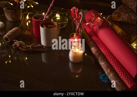 Warme und gemütliche Urlaubsatmosphäre mit heißer Schokolade, Kerzen, Zuckerstangen und Geschenkpapier. Stockfoto