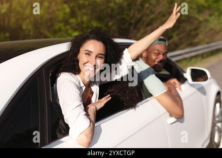 Die besten Freunde aus verschiedenen Rassen, die zusammen mit dem Auto reisen, durch Fenster schauen und im Sommer eine lustige Reise machen Stockfoto