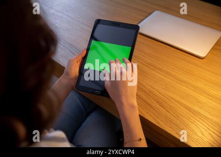 Eine Person, die mit einem Tablet mit grünem Bildschirm auf der Benutzeroberfläche beschäftigt ist Stockfoto