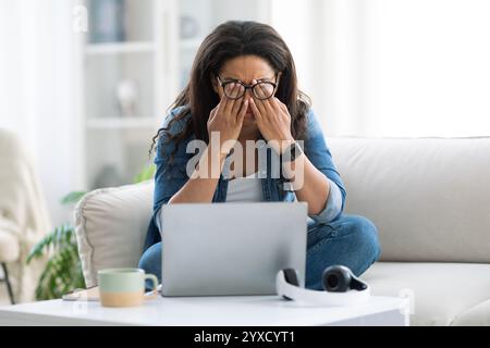 Frau, die am Morgen Stress erlebt, während sie am Laptop arbeitet Stockfoto