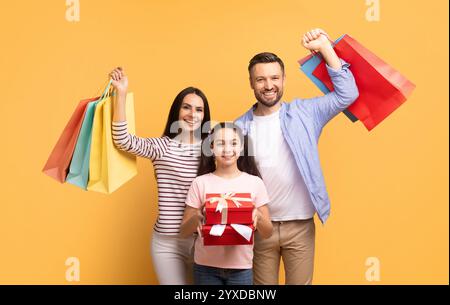Die Familie genießt einen fröhlichen Einkaufstag mit bunten Taschen und einem besonderen Geschenk Stockfoto