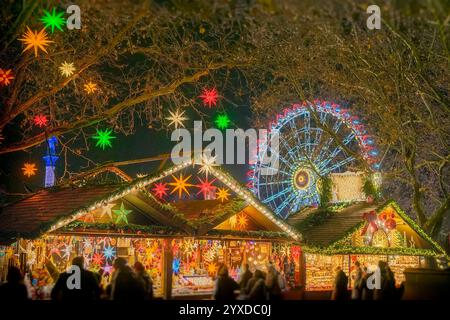 Weihnachtsmarkt in der Nacht mit hellen Lichtern, farbenfrohen Sternen und Riesenrad Stockfoto