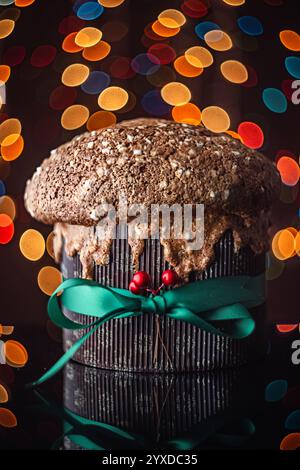 Italienischer Weihnachtskuchen Panettone, weiches traditionelles süßes Brot mit Nüssen, Rosinen und Schokolade gegen Retro-Bokeh-weihnachtsbeleuchtung Stockfoto