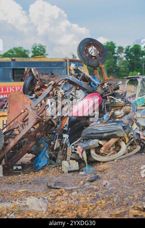 Balikpapan, Indonesien - 19. November 2024. Ein Haufen ausgemusterter Motorräder auf einem Schrottplatz, deren einst glänzende Oberflächen jetzt mit Rost bedeckt sind. Stockfoto