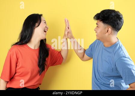 Two People junger asiatischer Freund Hi Five mit glücklichem aufgeregtem Gesicht auf gelbem Hintergrund Stockfoto