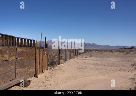 Ein rustikaler Holzzaun erstreckt sich über die karge Wüste im Wonder Valley, CA. Verwittert von Zeit und Elementen Stockfoto