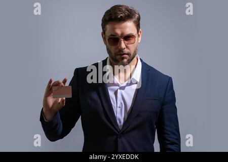 Kreditkartenkonzept. Kaukasischer Millennials erfolgreicher 40s-Geschäftsmann mit Bankkarte isoliert auf grauem Hintergrund, Studioporträt. Leute-Lifest Stockfoto