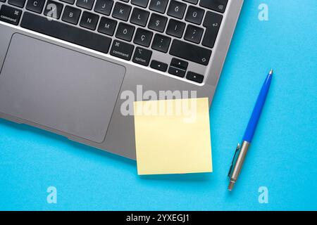 Draufsicht des leeren Post-it-Dokuments, das auf dem Laptop auf dem blauen Tisch feststeckt Stockfoto