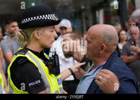 PA REVIEW OF THE YEAR 2024 Aktenfoto vom 24.03.08.24: Ein Polizeibeamter spricht mit einem Mann, während Menschen auf dem Nottingham Market Square nach den Messerstechangriffen in Southport protestieren, bei denen drei kleine Kinder getötet wurden. Ausgabedatum: Montag, 16. Dezember 2024. Stockfoto