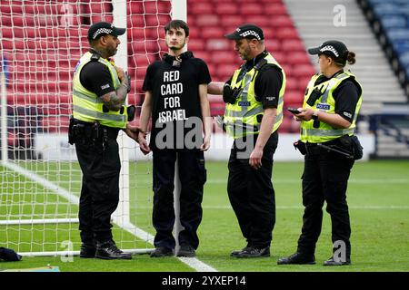 PA REVIEW OF THE YEAR 2024 Dateifoto vom 24.05.31: Die Polizei spricht mit einem Demonstranten, der ein T-Shirt mit der „Roten Karte für Israel“ trägt, nachdem sie sich vor dem Spiel der UEFA Women's Euro 2025 in Hampden Park, Glasgow, an einen Torpfosten gekettet hatten. Ausgabedatum: Montag, 16. Dezember 2024. Stockfoto