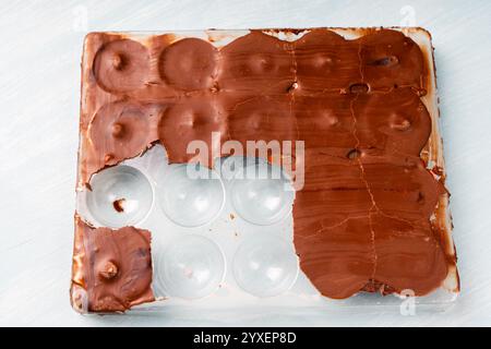 Die Form für die Herstellung von Schokoladenbonbons ist mit verfestigter Schokolade und fertigen Süßigkeiten in rosafarbener Glasur gefüllt. Hausgemachtes Schokoladenrezept. Hohe Qualität Stockfoto