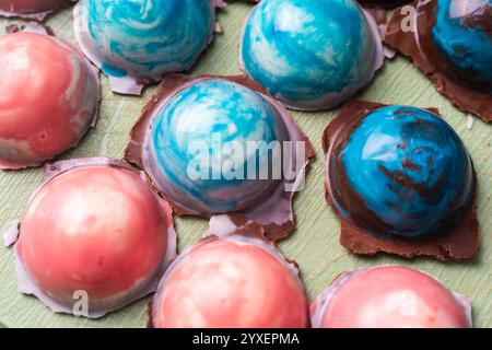 Verschiedene handgemachte farbige Pralinen auf grünem Hintergrund. Produktkonzept für Chocolatier. Hochwertige Fotos Stockfoto