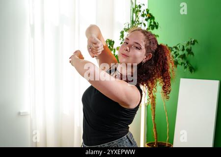 Eine junge Frau mit lockigen roten Haaren posiert für ein Foto in ihrem Haus Stockfoto