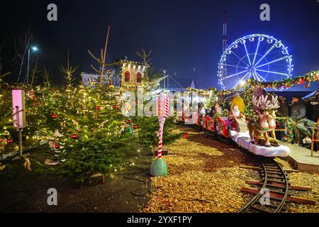 London, Großbritannien. Dezember 2024. Kinder und Familien genießen eine Fahrt in einem festlichen Miniaturzug. Cranger Weihnachtszauber ist einer der größten mobilen Weihnachtsparks in Europa und bietet einen traditionellen deutschen Weihnachtsmarkt mit Ständen, eine Vergnügungsmesse mit Fahrgeschäften, eine Eislaufbahn, Lebensmittel- und Getränkemärkte, Eisstockschießen, kostenlose Kindershows, Weihnachtsfiguren und einen Santa-Schlitten mit Rentieren, die über die Messe fliegen. Sie läuft bis Dezember 30. Quelle: Imageplotter/Alamy Live News Stockfoto