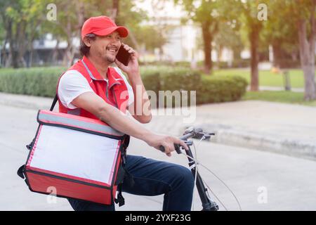 Lebensmittelversand, Beruf und Menschenkonzept - Liefermann mit wärmeisolierter Tasche und Fahrrad auf der Straße der Stadt telefonisch auf dem Smartphone Stockfoto