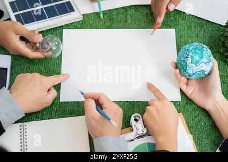Solarmodellmodell und Glühbirne repräsentierten erneuerbare Energien und Erdmodell repräsentierte die Idee einer Öko-Stadt wurde auf dem grünen Business-Meeting-Tisch platziert Stockfoto