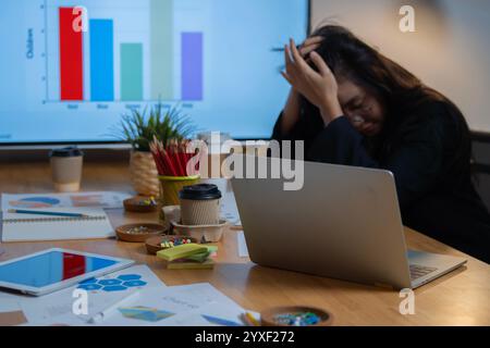 Ich habe versucht, dass der asiatische Büroangestellte sich gelangweilt, unglücklich fühlte und nachts im Büro arbeitete. Selektiver Fokus. Stockfoto