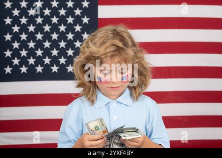 American Dollars Geldscheine Konzept. Der Junge hat eine Menge von hundert Dollar isoliert auf Studiohintergrund. Kind mit amerikanischer Flagge. Stockfoto
