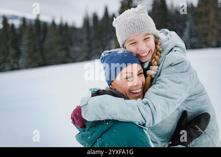 Mom und süßes Mädchen umarmen sich, stehen mitten in der schneebedeckten Natur. Stockfoto