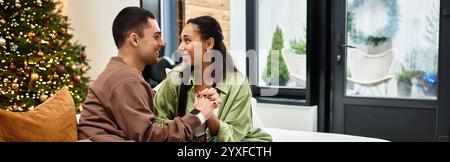 Ein schönes Paar teilt einen romantischen Moment in ihrem stilvoll eingerichteten Apartment während der Feiertage, Banner Stockfoto