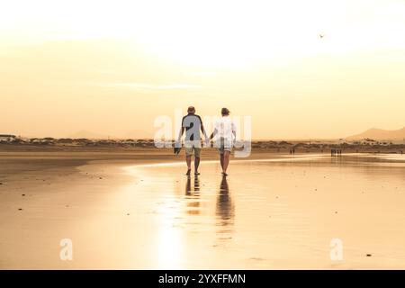 Glückliches, romantisches älteres Ehepaar, das den wunderschönen Sunset Walk am Strand genießt. Travel Vacation Rente Lifestyle Konzept Stockfoto