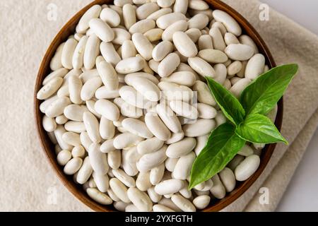 Blick von oben auf weiße Bohnen in einer Holzschale. Weiße Kidneybohnen, marineblaue Bohnen, Haricot zum Kochen von vegetarischen Gerichten aus gebackenen Bohnen. Pflanzenprotein, Ernte Stockfoto