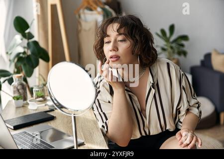 Eine junge Frau trägt Lippenstift in einer sonnendurchfluteten Wohnung und blickt sich im Spiegel an. Stockfoto