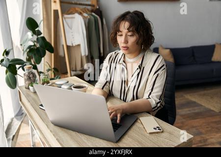 Eine junge Frau mit lockigen Haaren arbeitet intensiv in ihrer hellen, schicken Wohnung. Stockfoto