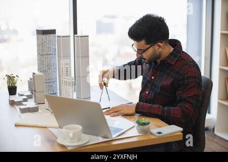 Indischer Architekt in modernen Büros misst das Stadtmodell, das Kreativität und Präzision im Designprozess demonstriert und architektonische Fähigkeiten hervorhebt. Stockfoto