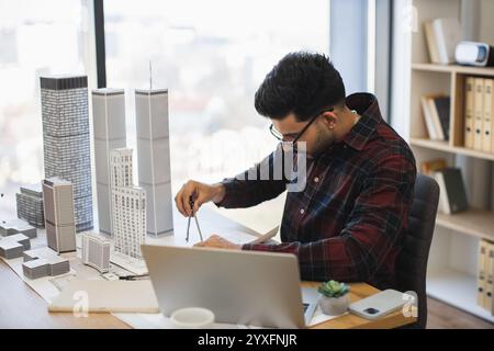 Indischer Architekt in modernen Büros misst das Stadtmodell, das Kreativität und Präzision im Designprozess demonstriert und architektonische Fähigkeiten hervorhebt. Stockfoto
