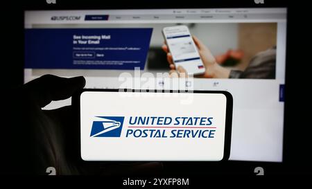 In dieser Abbildung befindet sich ein Mobiltelefon mit dem Logo der US-amerikanischen Agentur United States Postal Service (USPS) vor der Webseite. Stockfoto