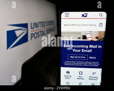 In dieser Abbildung hält eine Person ein Smartphone mit der Webseite der US-amerikanischen Agentur United States Postal Service (USPS) vor dem Logo. Stockfoto