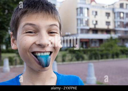 Der 12-jährige Junge stach seine blaue, nahrungsfarbene Zunge aus. Das Konzept der Lebensmittelfarbstoffe in Kinderbonbons, künstliche Lebensmittelzusatzstoffe, al Stockfoto