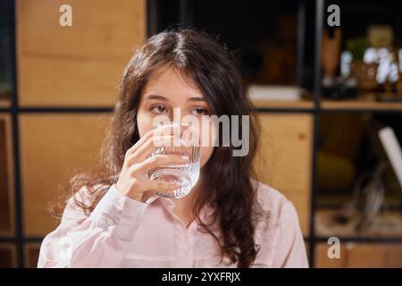 Die junge schöne Frau nimmt Pillen und Vitamine im Büro. Geschäftsfrau kümmert sich um Gesundheit und trinkt Medikamente. Stockfoto