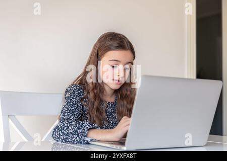 Ein trauriges Mädchen arbeitet an einem Laptop. Trauriges Mädchen und Laptop. Technologiekonzept. Stockfoto